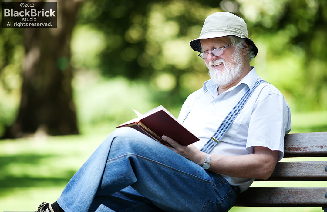 Portrait of senior reading a book in the park